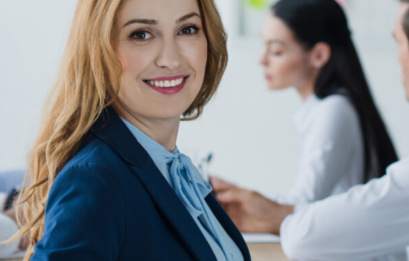 Selective Focus Of Smiling Businesswoman And Colleagues At Workplace In Office